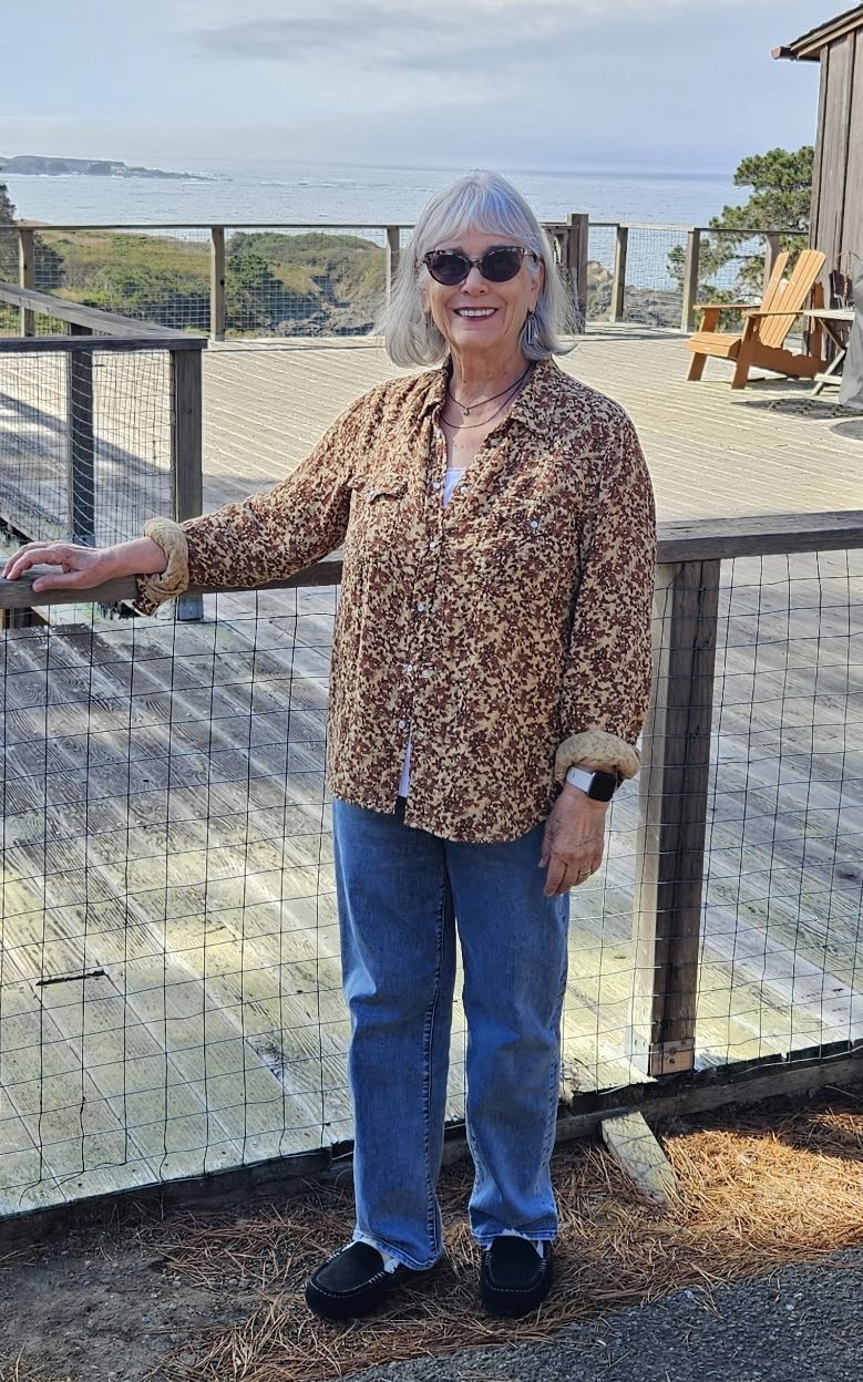 Cathryn Shea on a wooden deck above the ocean, one hand on the rail
