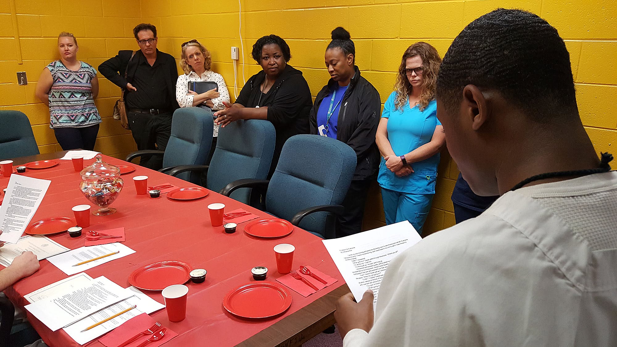 A Prison Writes session around a long red table, pages and plates set out